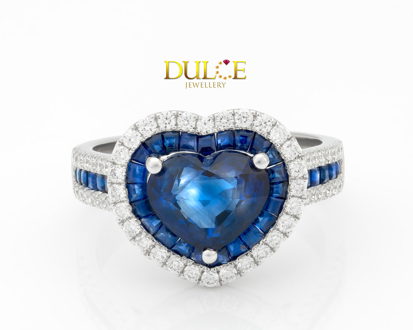 "Heart-shaped royal blue sapphire surrounded by a halo of small blue sapphires and sparkling diamonds in a polished gold setting."