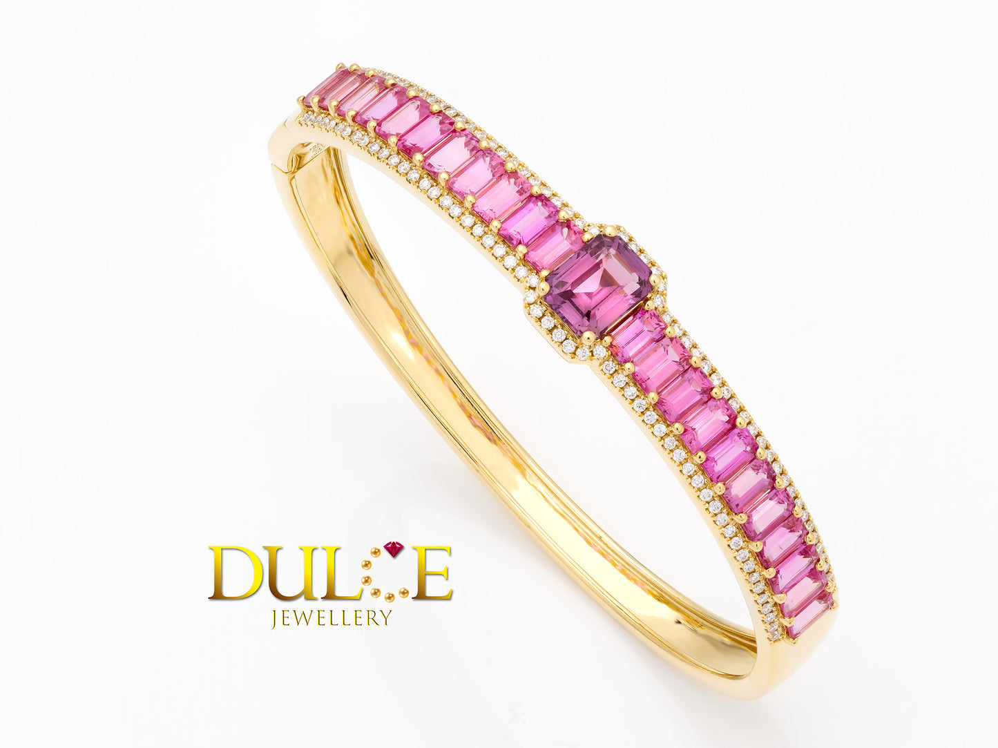 Elegant 18K gold bangle featuring a vibrant hot pink sapphire, showcasing a sophisticated and luxurious design.