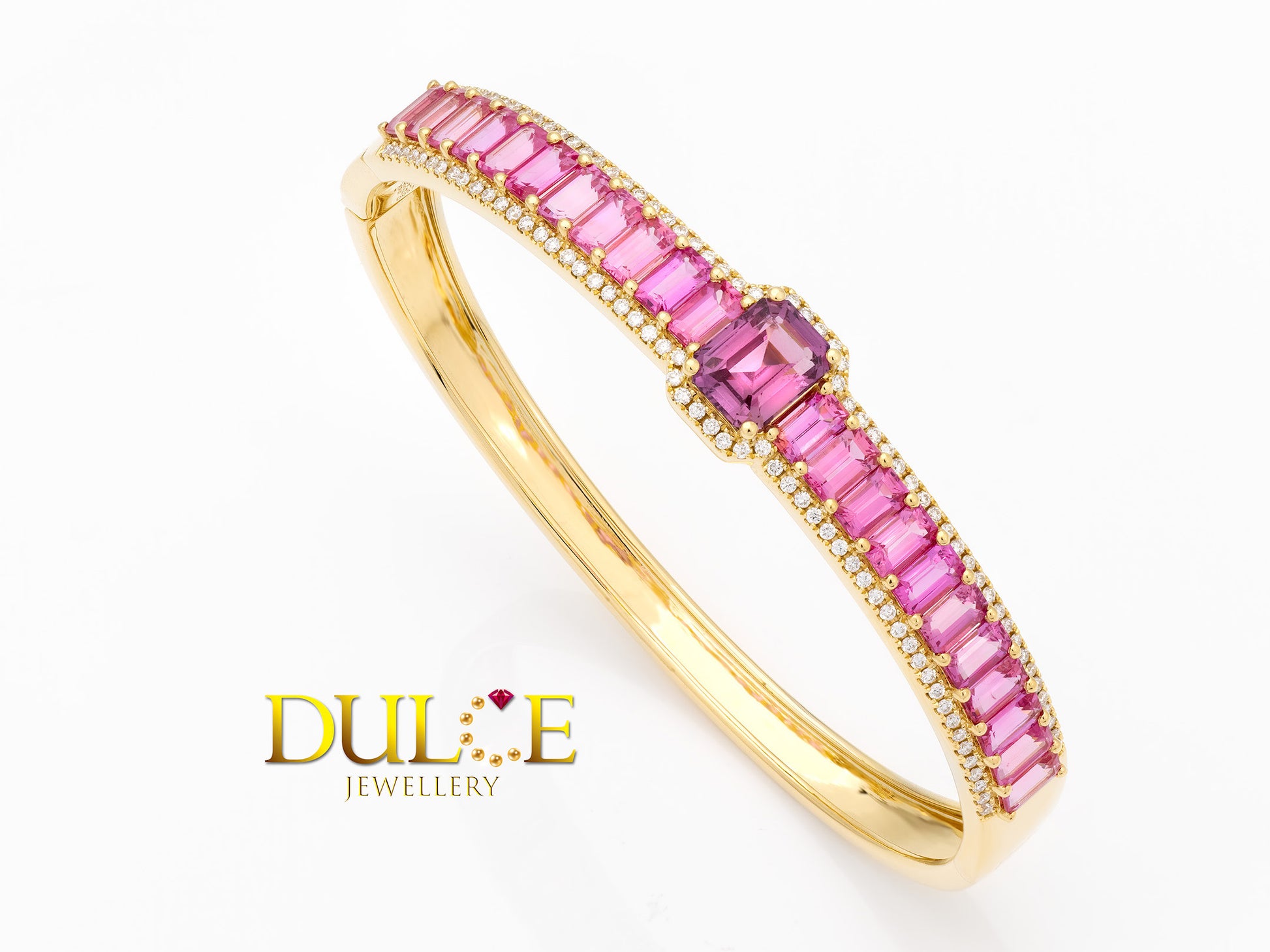 Elegant 18K gold bangle featuring a vibrant hot pink sapphire, showcasing a sophisticated and luxurious design.